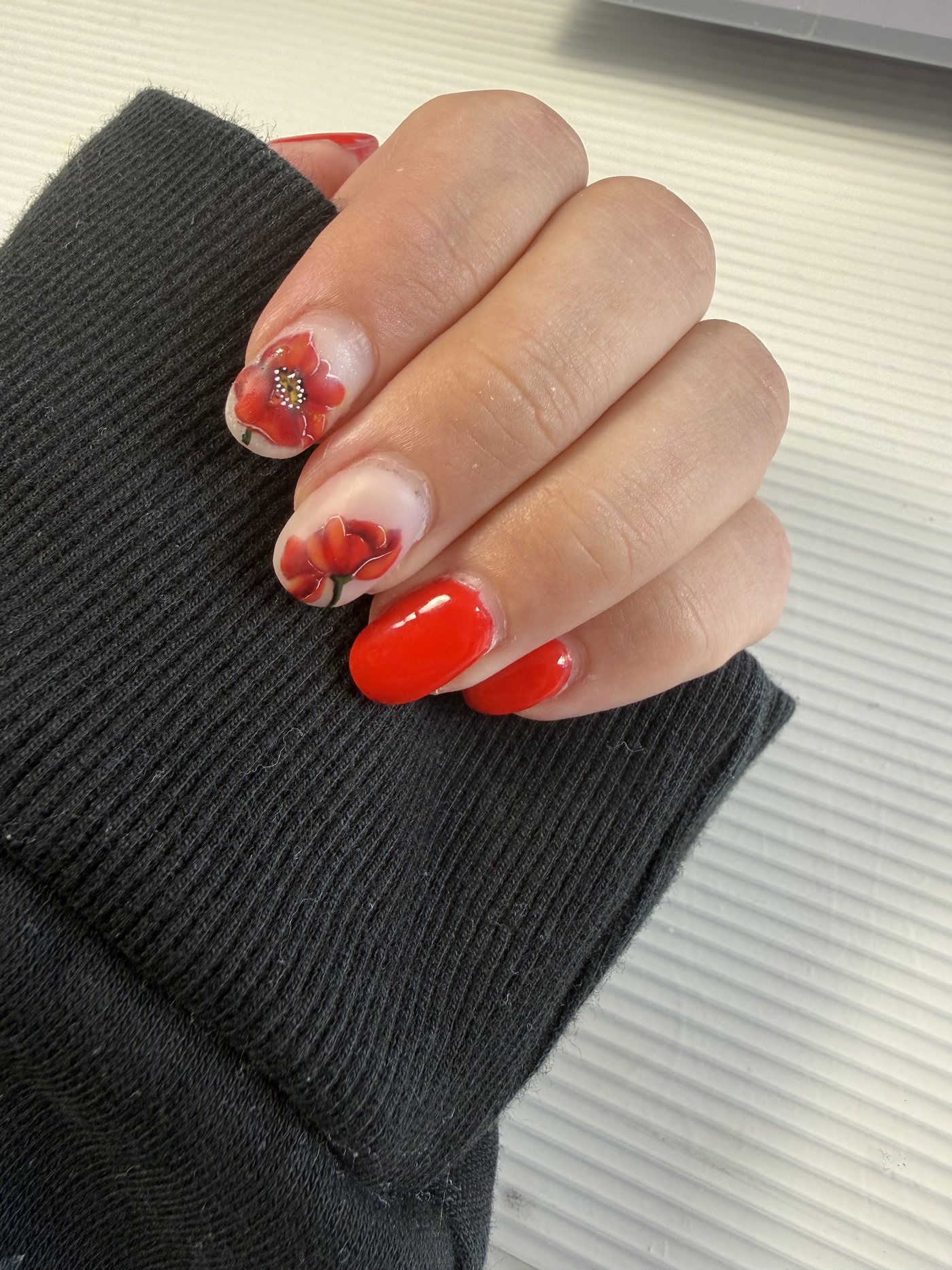 Hand met rode nagels en handgeschilderde klaprozen