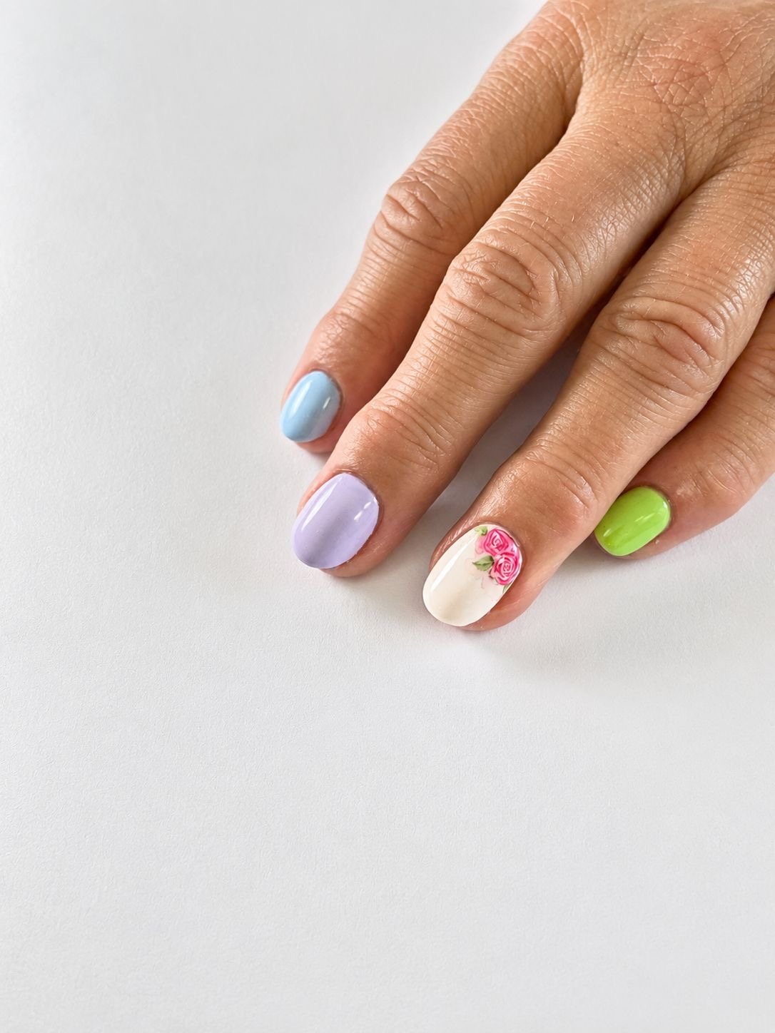 Pastel gellak in lichtblauw, lila en groen met een handgeschilderd bloemetje