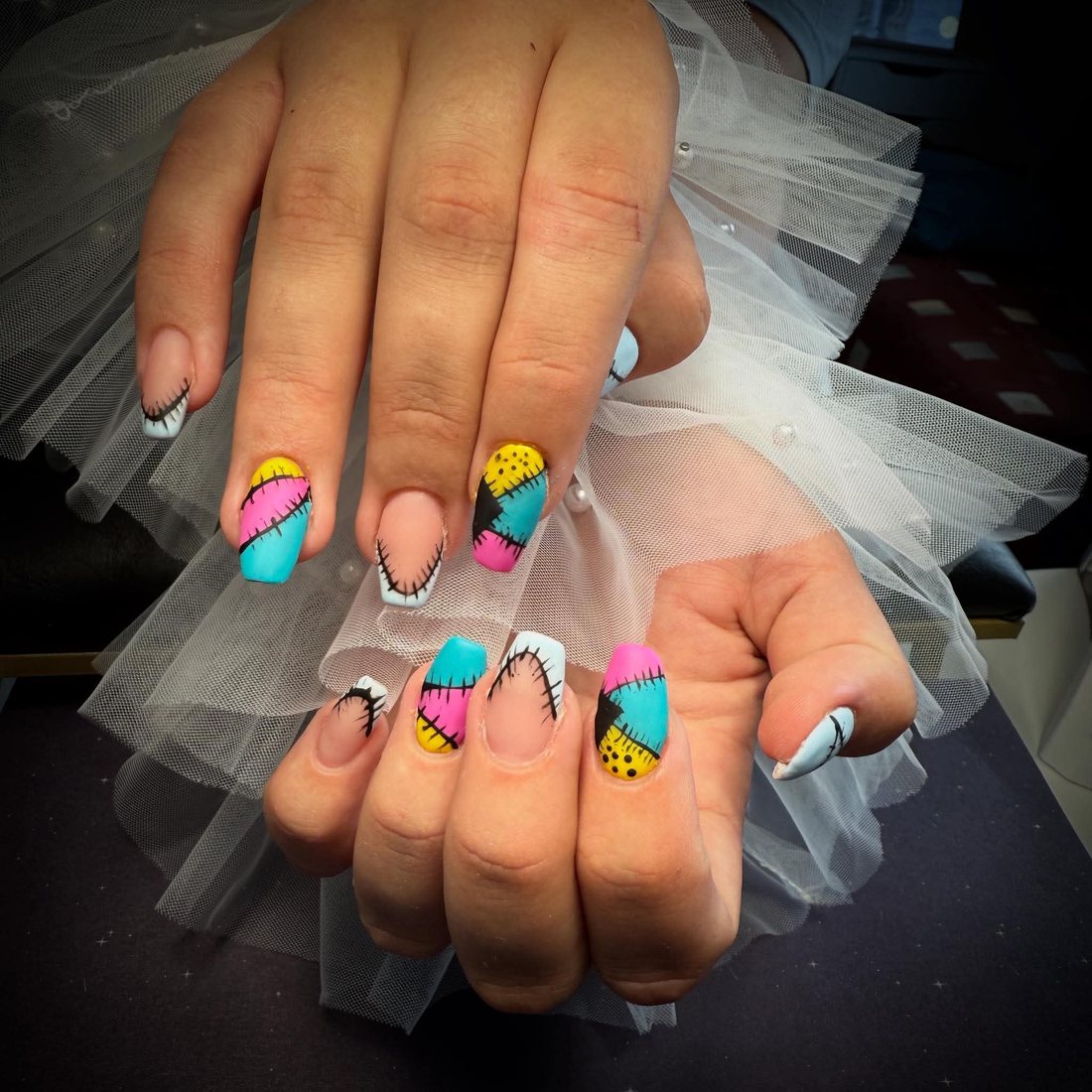 Kleurrijke patchwork nail art met gestikte lijntjes op amandelnagels