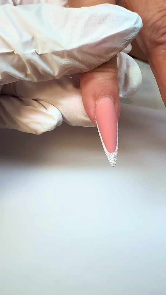 Nude stiletto nagel met een witte glitterrand